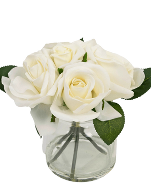 Le Bouquet de Roses Artificielles Real Touch Blanc 18 cm est un petit vase en verre transparent avec des roses blanches et des feuilles vertes réalistes, sur un fond blanc uni.