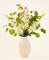 Bouquet de fleurs artificielles en soie Pure Harmony, composé de fleurs roses et blanches avec des feuilles vertes, disposées dans un vase nervuré de couleur crème.