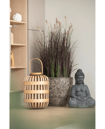 Une lanterne en bois, un grand pot en pierre avec un bonsaï d'oignon artificiel de 100 cm (ignifuge) et une statue de Bouddha grise sont disposés sur une surface de couleur claire, près d'une étagère en bois et d'un mur pâle.