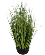 Het Kunstgras Dogtail uiengras Bran 90 cm brandvertragend is een zwarte pot met dichte, hoge, dunne, groene, grasachtige bladeren die rechtop staan, afgebeeld tegen een witte achtergrond.